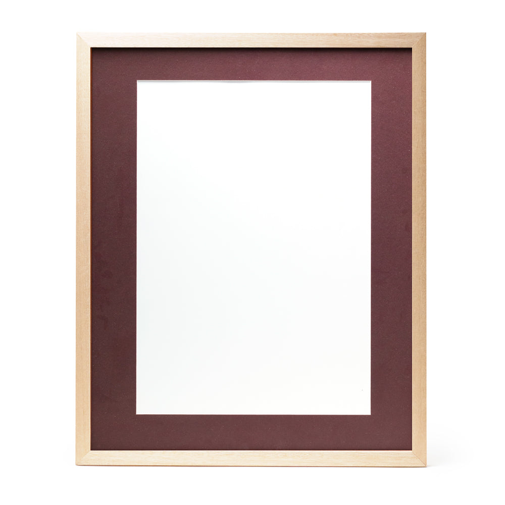 A wooden frame with natural stain finish and a burgundy red pre-cut framing matt.