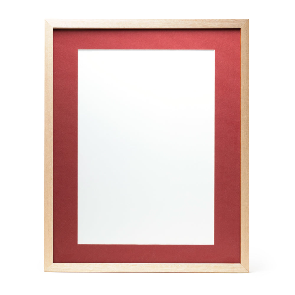 A wooden frame with natural stain finish and a deep red pre-cut framing matt.